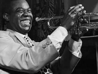 Louis Armstrong souriant et tenant sa trompette