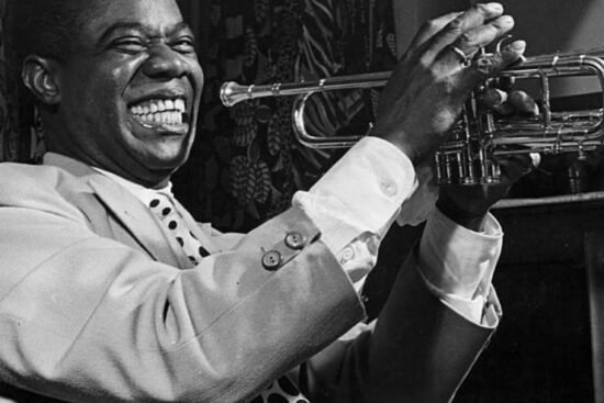 Louis Armstrong souriant et tenant sa trompette