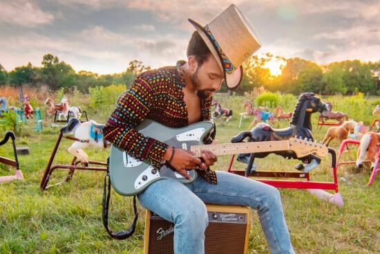 Dwayne Haggins, guitare de blues-rock dans un champ avec sa guitatre.