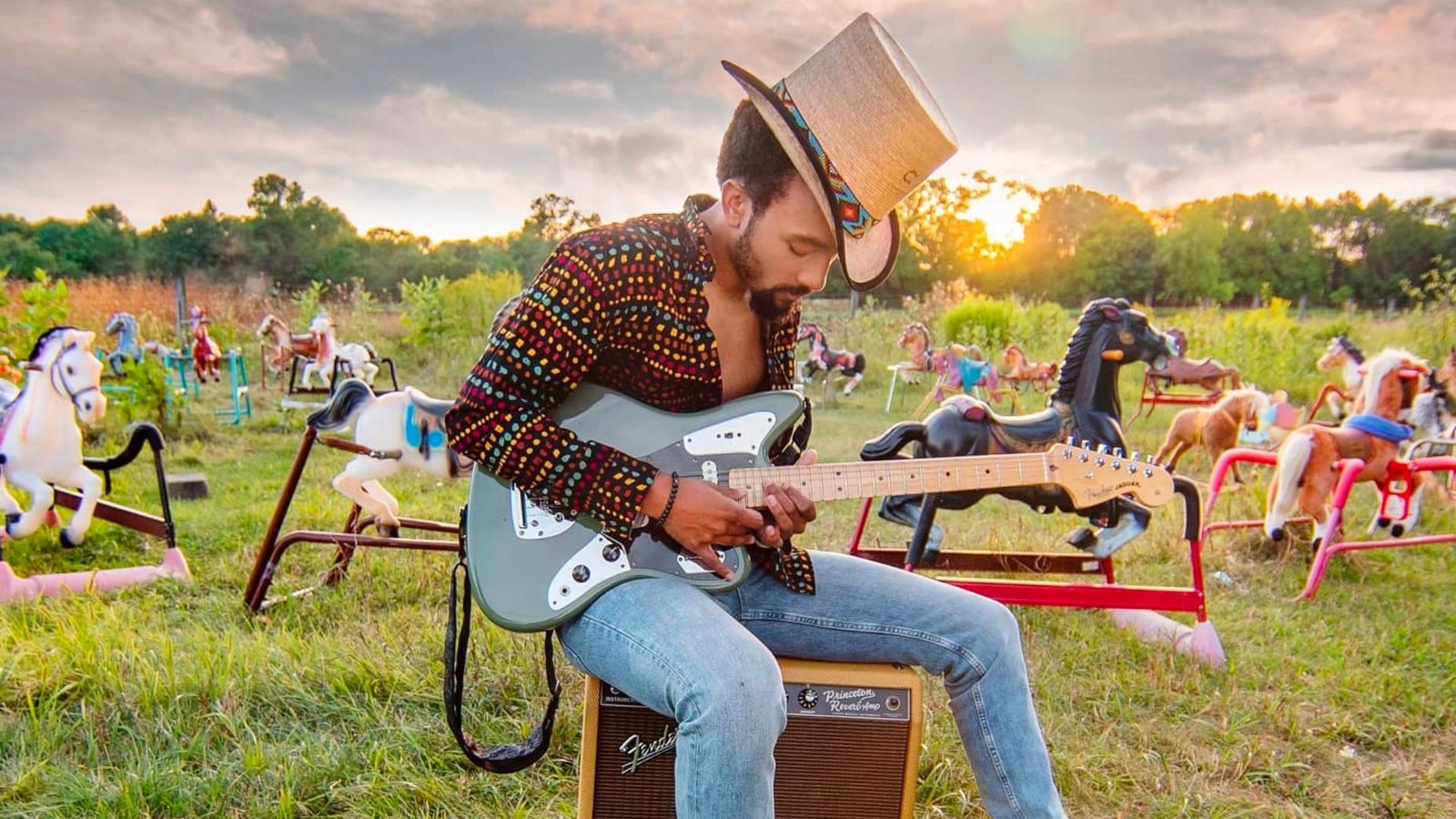 Dwayne Haggins, guitare de blues-rock dans un champ avec sa guitatre.