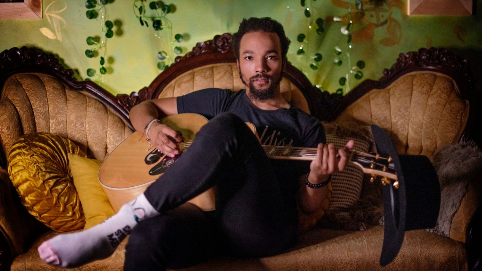 Dwayne Haggins avec sa guitare dans un canapé